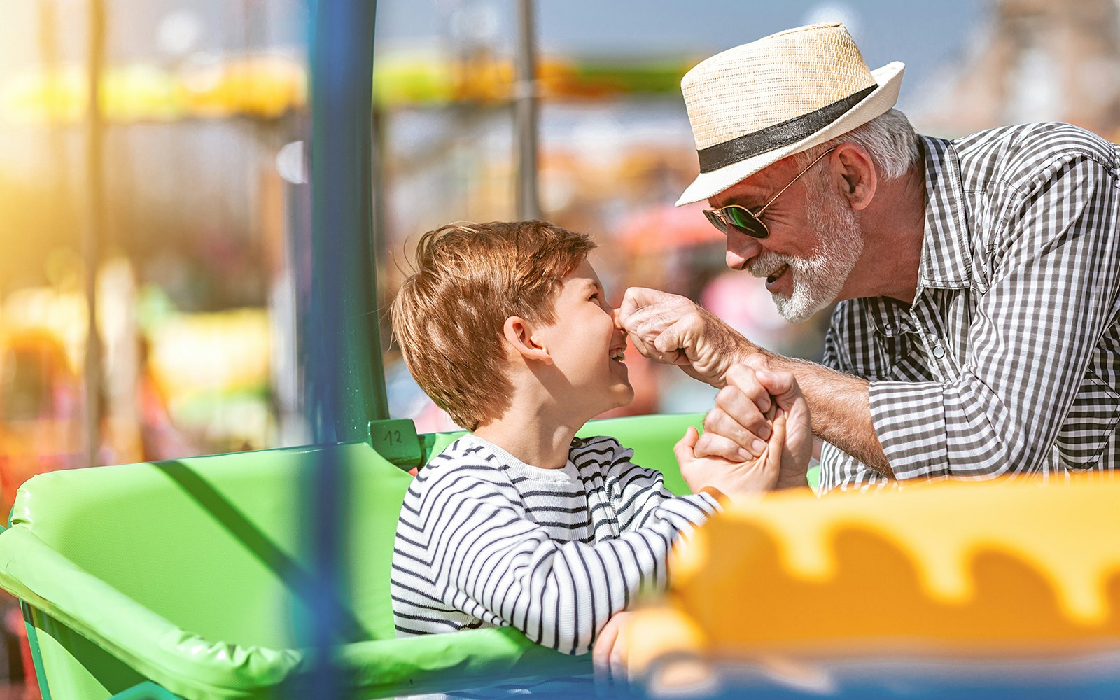 Grandfather and grandson enjoying a ride at an amusement park.