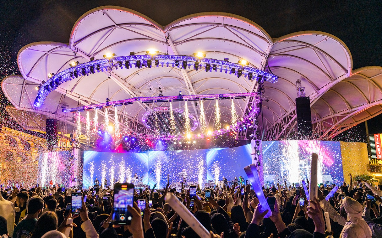 Crowd enjoying a vibrant night show with fireworks at Global Village Dubai.