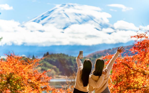 Tourists using a smartphone with Mount Fuji in the background, Japan.