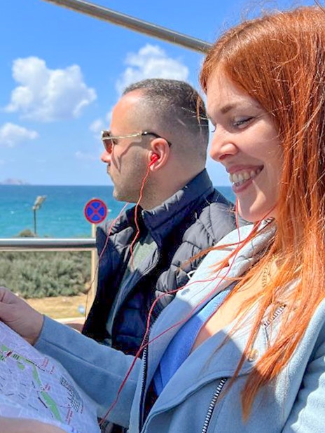 Tourists enjoying Heraklion Hop-On Hop-Off Bus Tour with sea view and map.