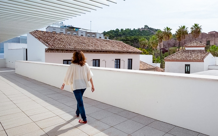 Visitor walking on the terrace of the Picasso Museum in Malaga, with cityscape views.