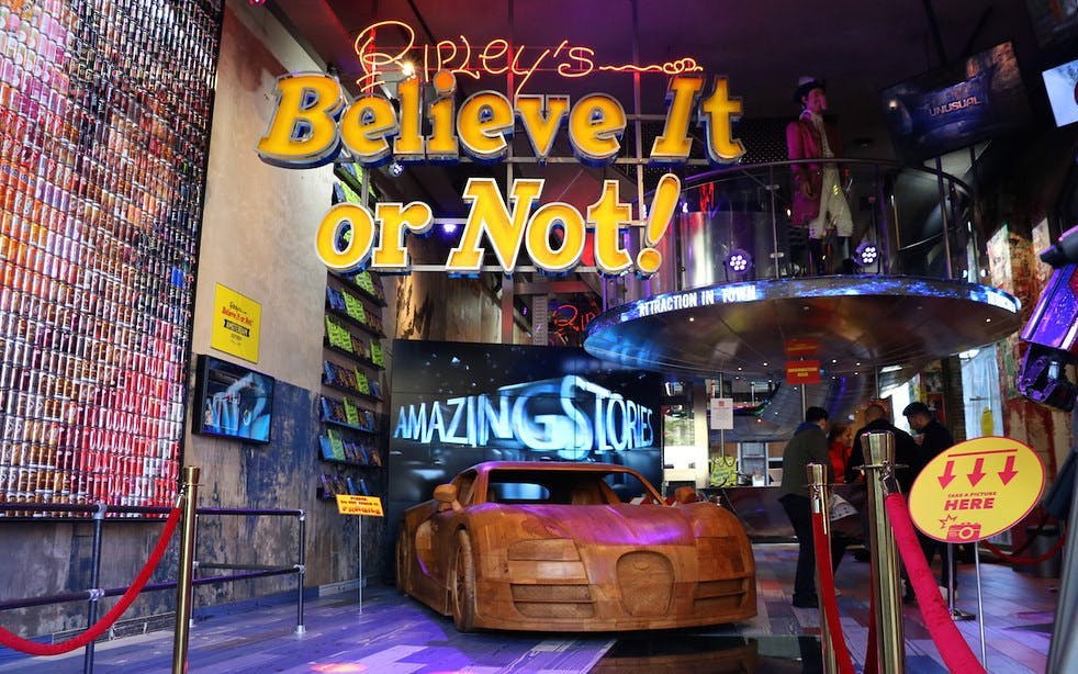Ripley's Believe It or Not! entrance with wooden car exhibit and visitors exploring.