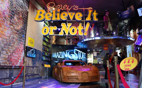 Ripley's Believe It or Not! entrance with wooden car exhibit and visitors exploring.