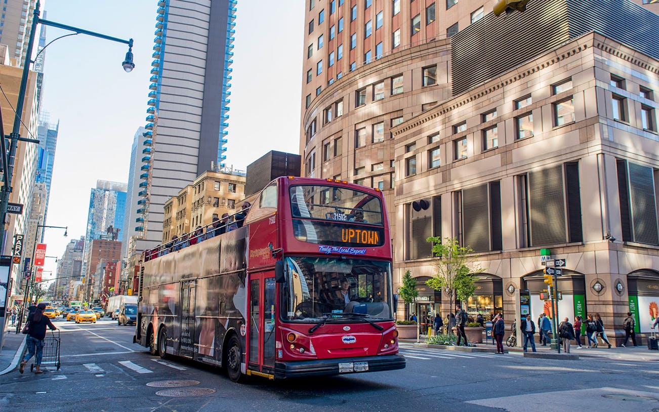 Red double-decker bus on a New York City street during a hop-on hop-off tour.