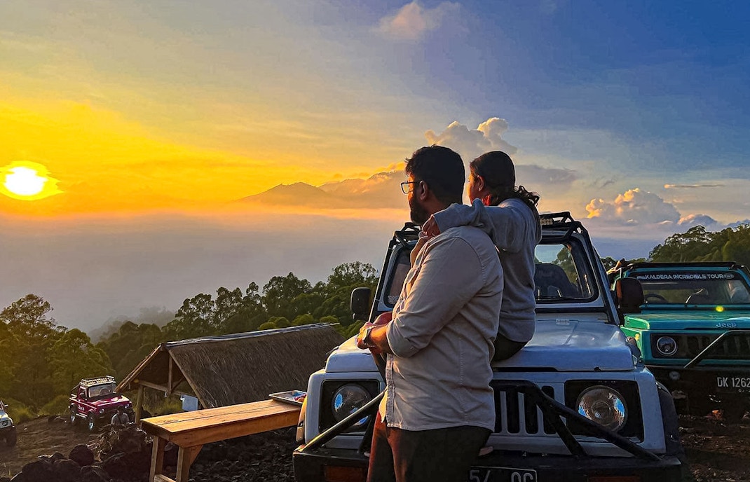 Couple watching sunrise near Mount Batur in Jeep