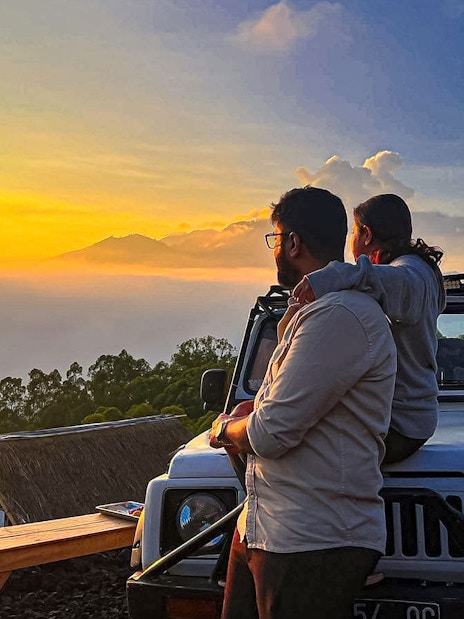 Couple in Jeep watching sunrise near Mount Batur, Bali.