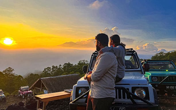 Couple in Jeep watching sunrise near Mount Batur, Bali.