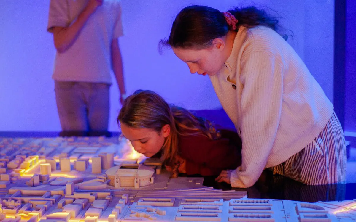 Children exploring a lit-up scale model of Amsterdam.