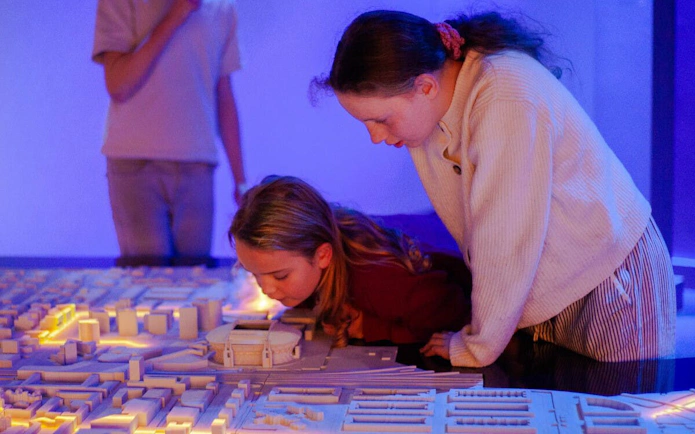 Children exploring a lit-up scale model of Amsterdam.