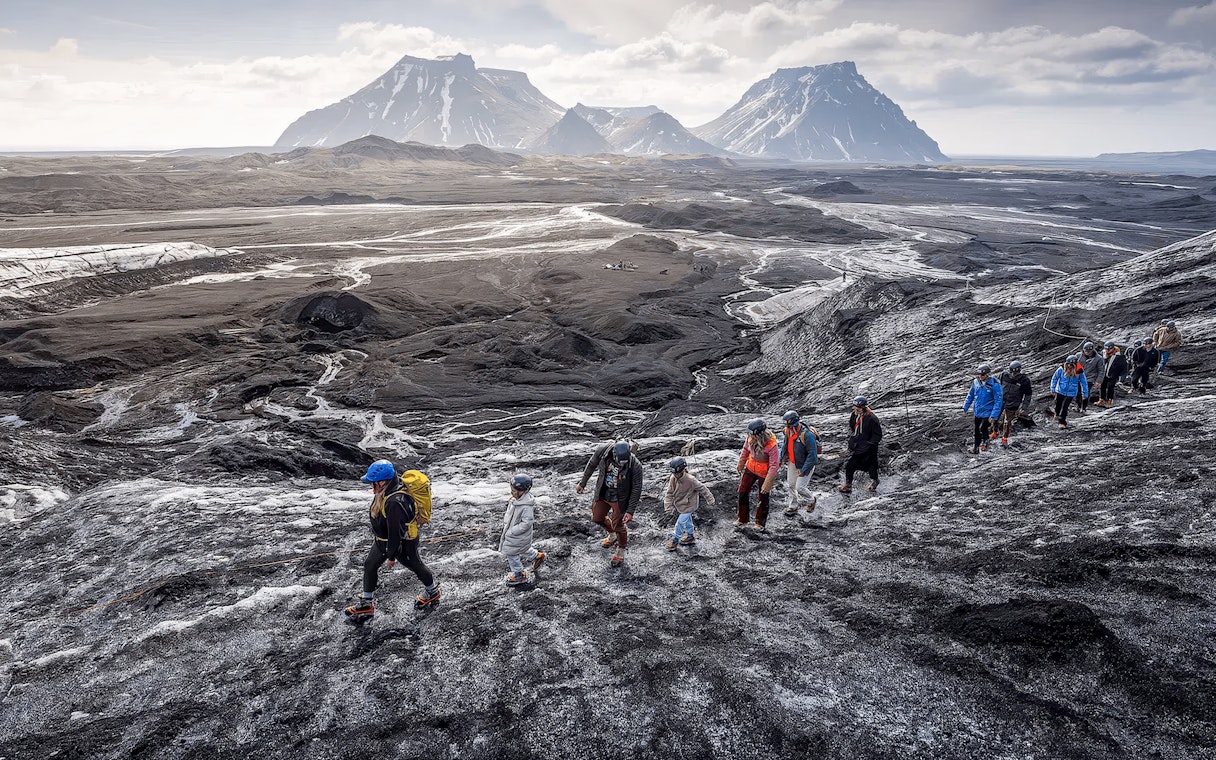 Tourists hiking on volcanic terrain near Katla Volcano, Iceland.