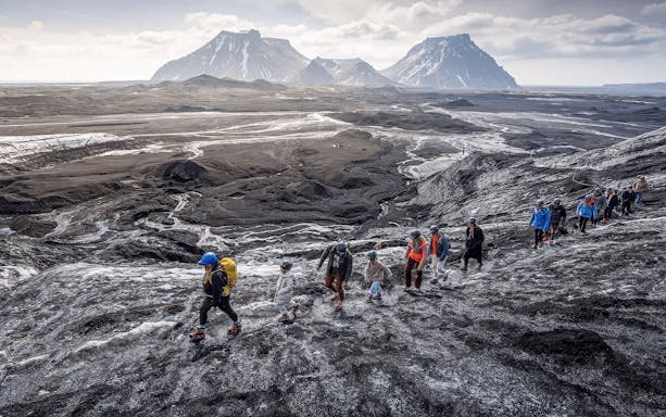 Tourists hiking on volcanic terrain near Katla Volcano, Iceland.