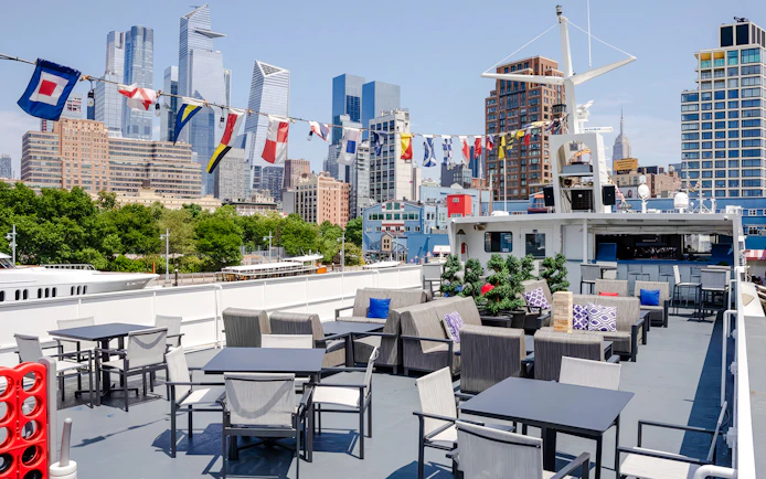 Outdoor seating on New Jersey Signature Cruise with city skyline in background.
