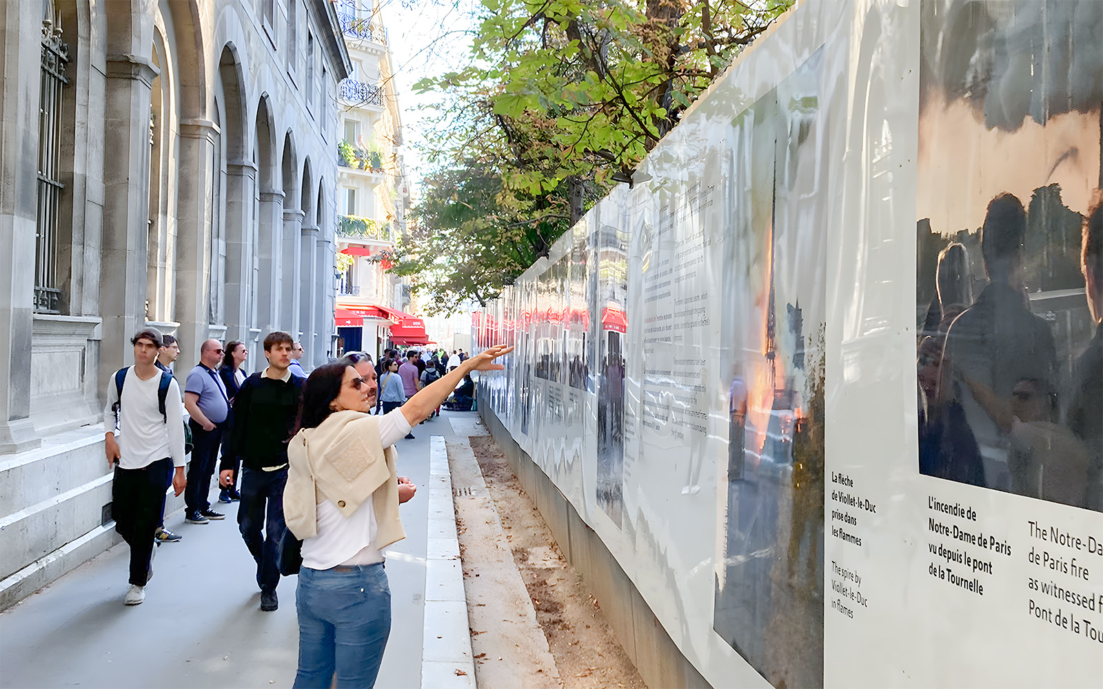 Visitors on a Notre Dame walking tour examining historical displays along a Paris street.