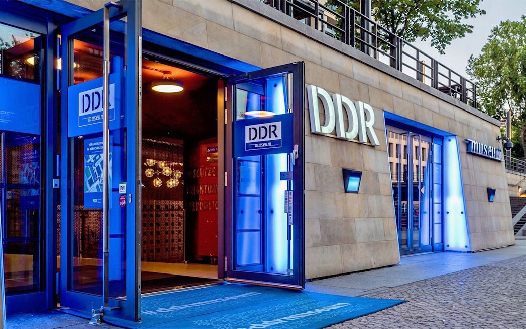DDR Museum entrance in Berlin with illuminated signage and open doors.