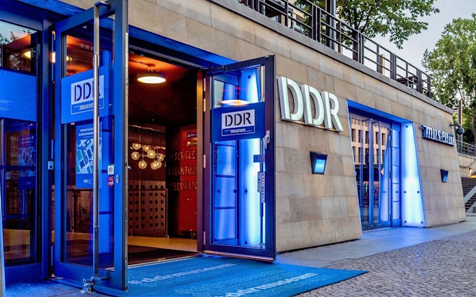 DDR Museum entrance in Berlin with illuminated signage and open doors.
