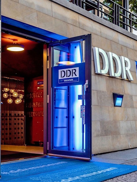 DDR Museum entrance in Berlin with illuminated signage and open doors.