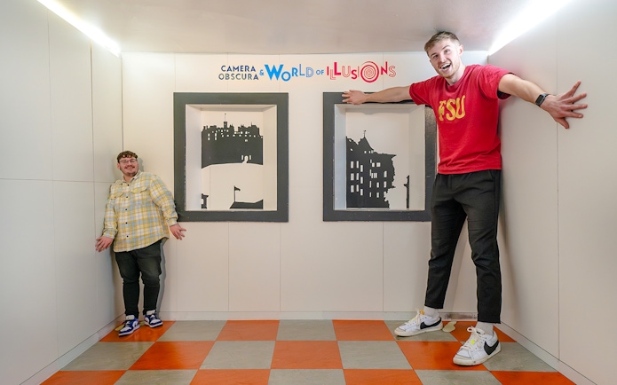 Visitors experiencing size illusion in Ames Room at Camera Obscura & World of Illusions, Edinburgh.