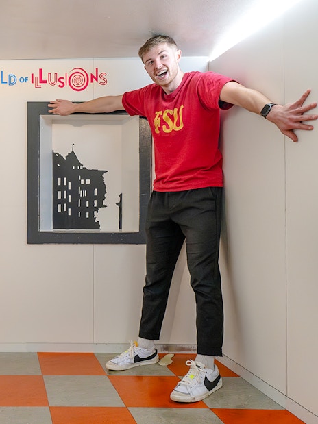 Visitors experiencing size illusion in Ames Room at Camera Obscura & World of Illusions, Edinburgh.