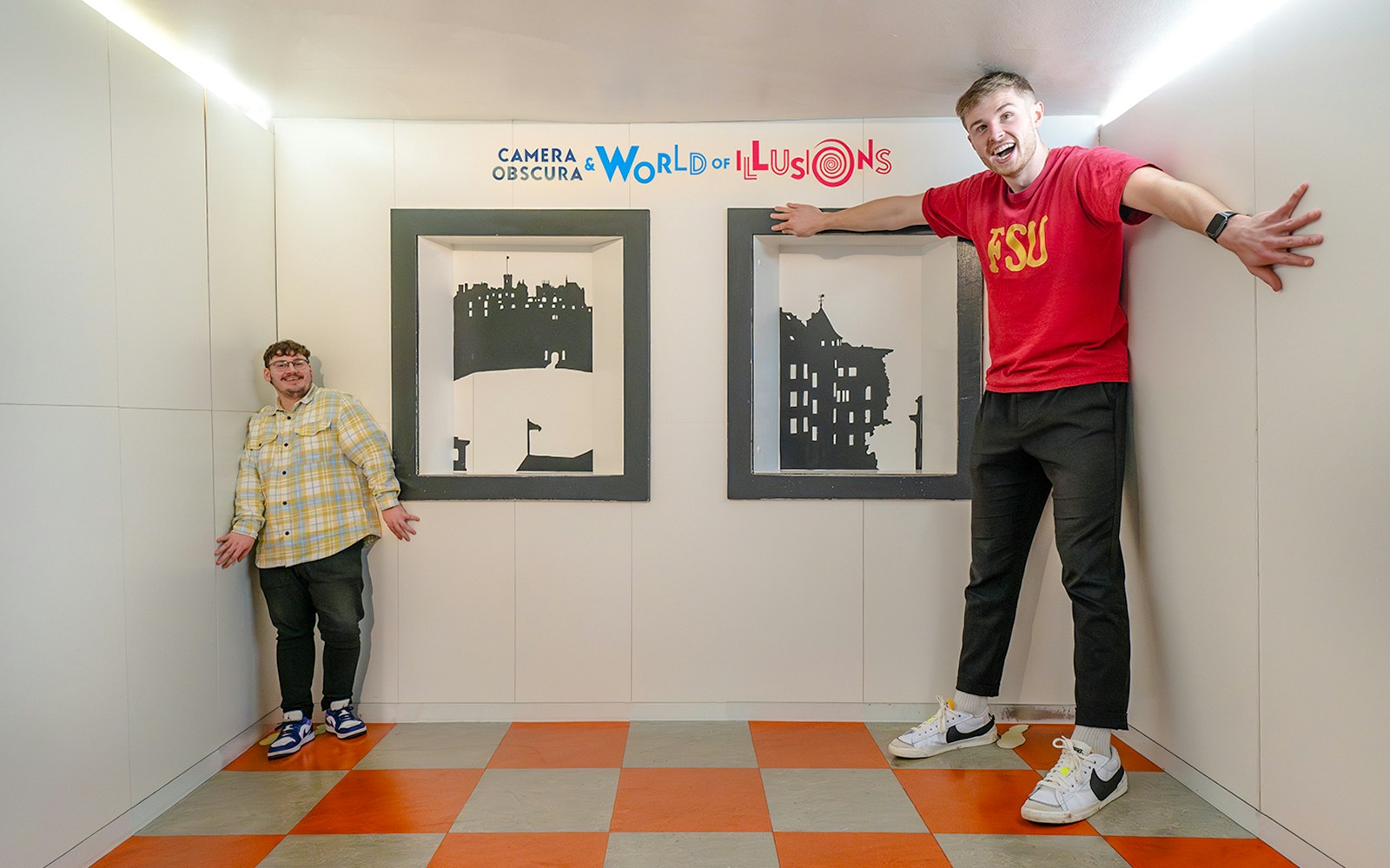 Visitors experiencing size illusion in Ames Room at Camera Obscura & World of Illusions, Edinburgh.