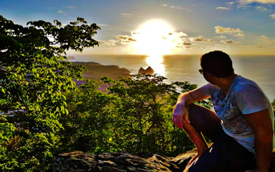 Sunset view from Noronha Piquinho Trail, overlooking ocean and greenery, Sao Paulo.