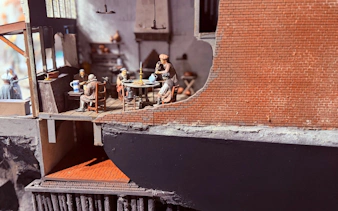 Miniature scene of people dining in a historical building interior.