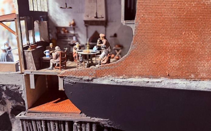 Miniature scene of people dining in a historical building interior.