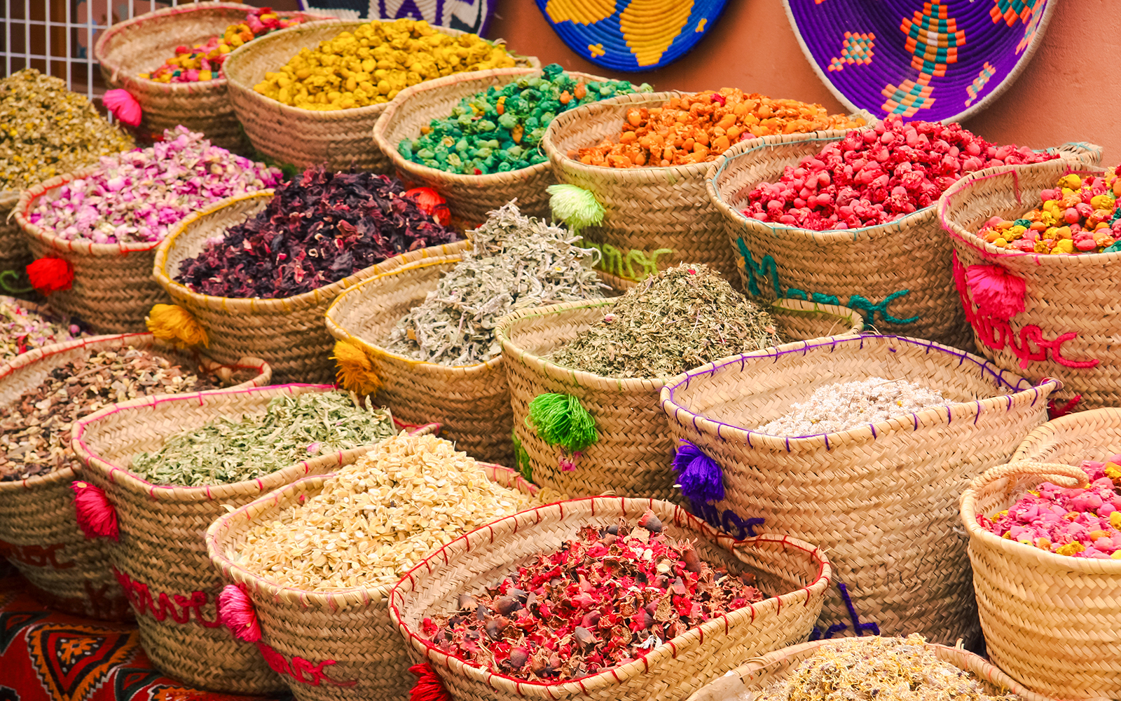 Baskets of colorful spices and herbs at a Marrakech market during a night walking tour.