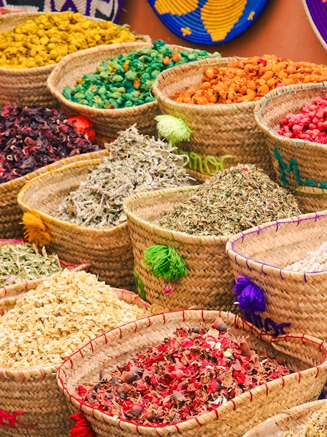 Baskets of colorful spices and herbs at a Marrakech market during a night walking tour.