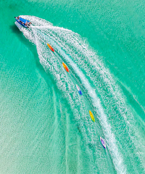 Aerial view of watersports activities on Fraser Island, K'gari, with kayaks trailing a speedboat.
