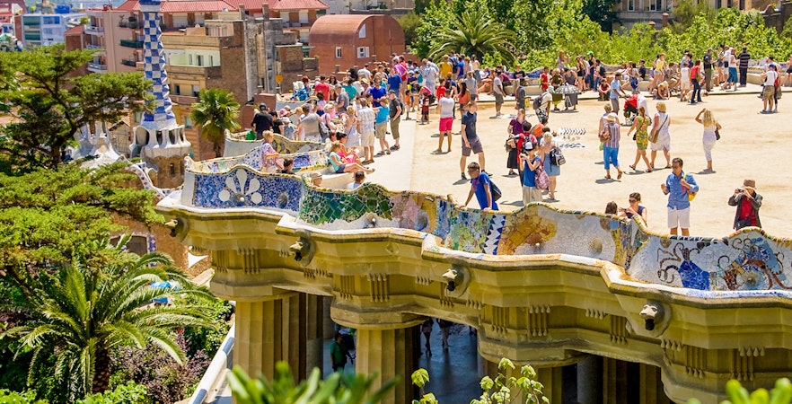 Park Güell terrace view overlooking Barcelona cityscape with colorful mosaic benches.