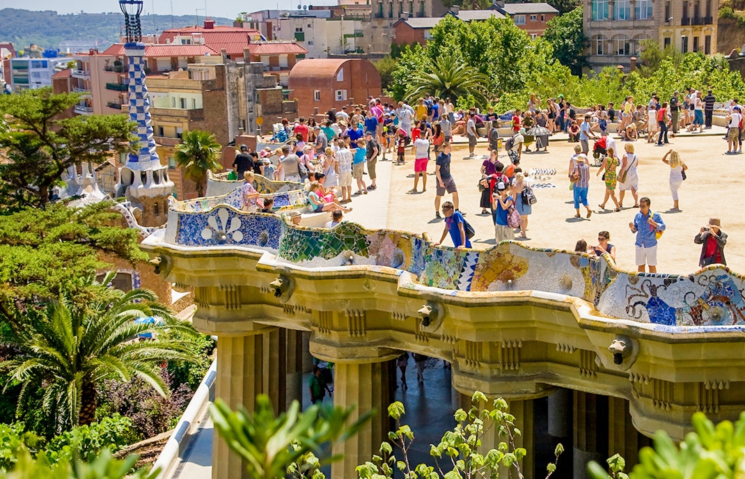 Park Güell terrace view overlooking Barcelona cityscape with colorful mosaic benches.