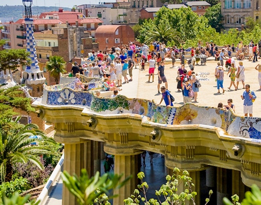 Park Güell terrace view overlooking Barcelona cityscape with colorful mosaic benches.