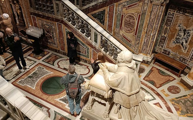 Statue of Pope Pius IX kneeling in prayer before the Holy Crib relics in a richly decorated chapel.