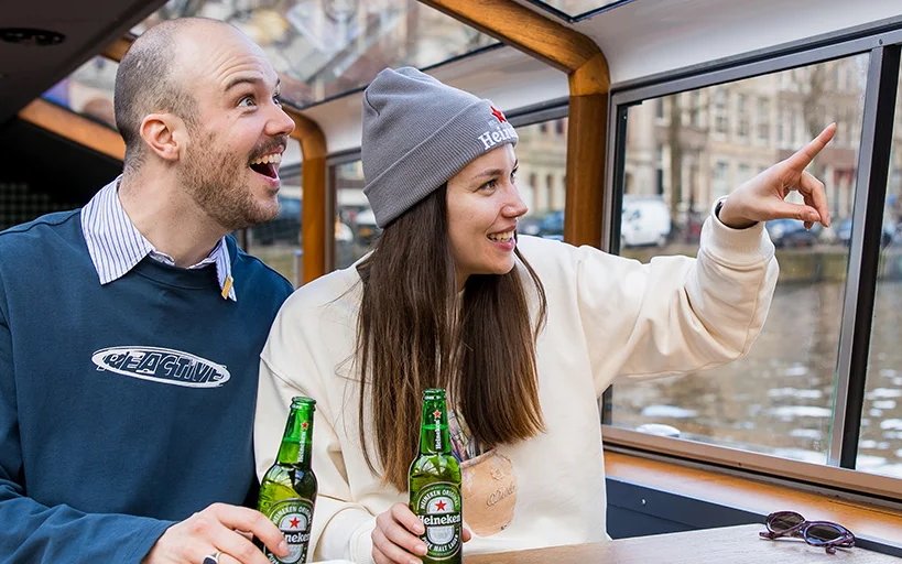 Couple enjoying Heineken Canal Cruise in Amsterdam with live guide.