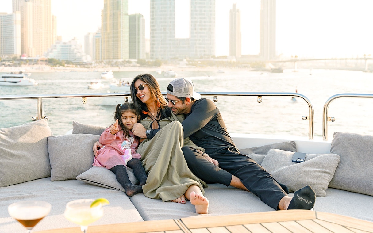 Family relaxing on a Sunseeker superyacht with city skyline in the background.