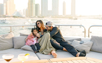 Family relaxing on a Sunseeker superyacht with city skyline in the background.