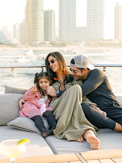Family relaxing on a Sunseeker superyacht with city skyline in the background.