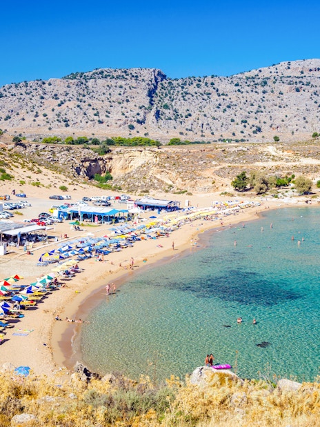 Agathi Beach on Rhodes Island with sun loungers and clear blue water.