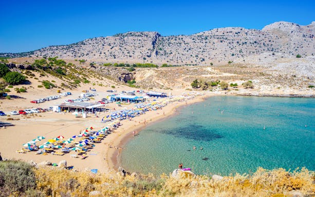 Agathi Beach on Rhodes Island with sun loungers and clear blue water.