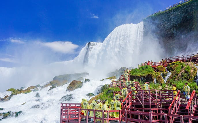 Visitors in raincoats on red walkways at Cave of the Winds, Niagara Falls.