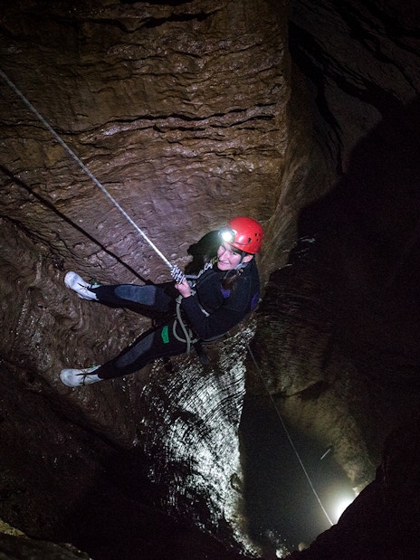 Person abseiling in a dark cave during a guided black water rafting experience in Waitomo.