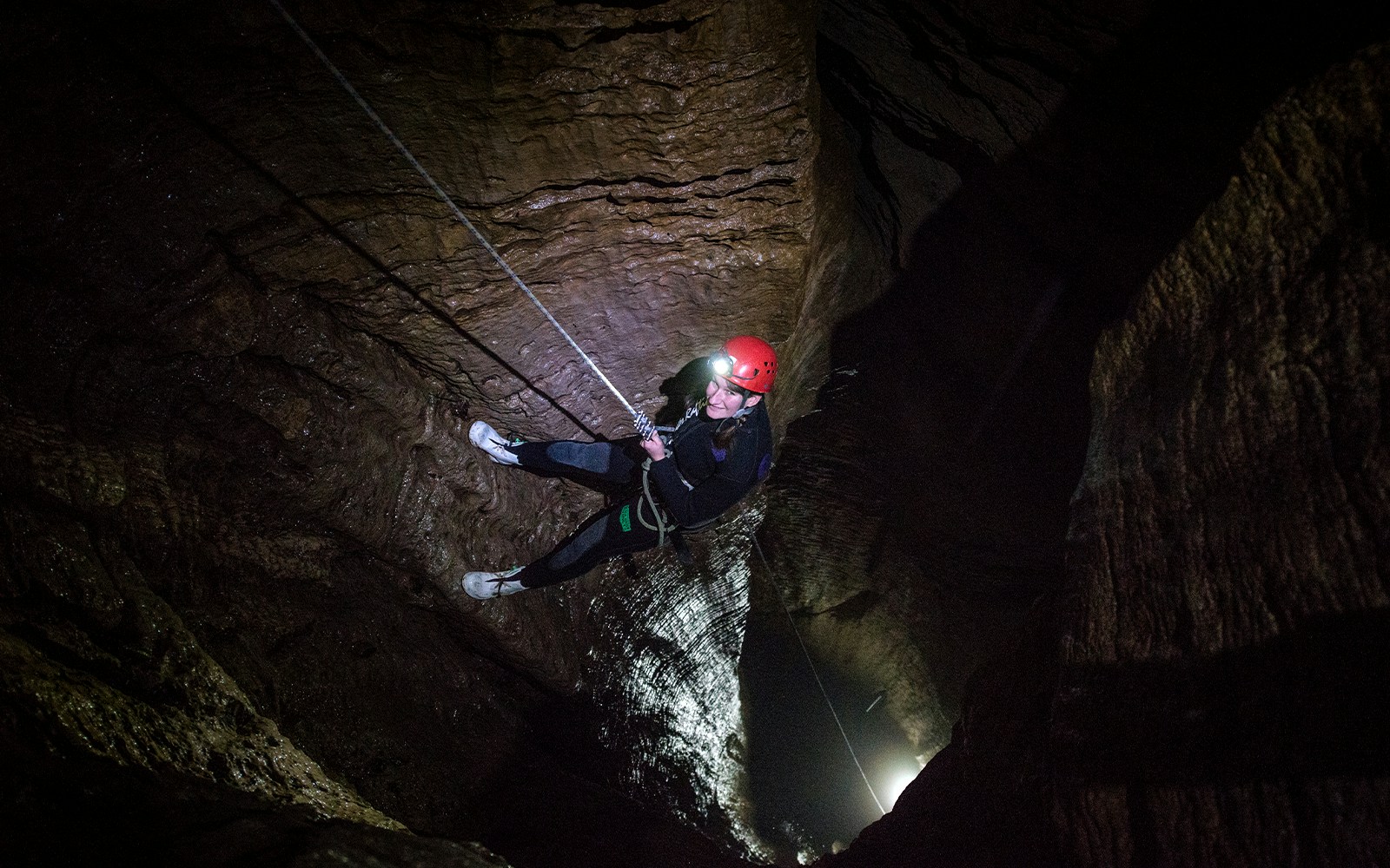 Person abseiling in a dark cave during a guided black water rafting experience in Waitomo.