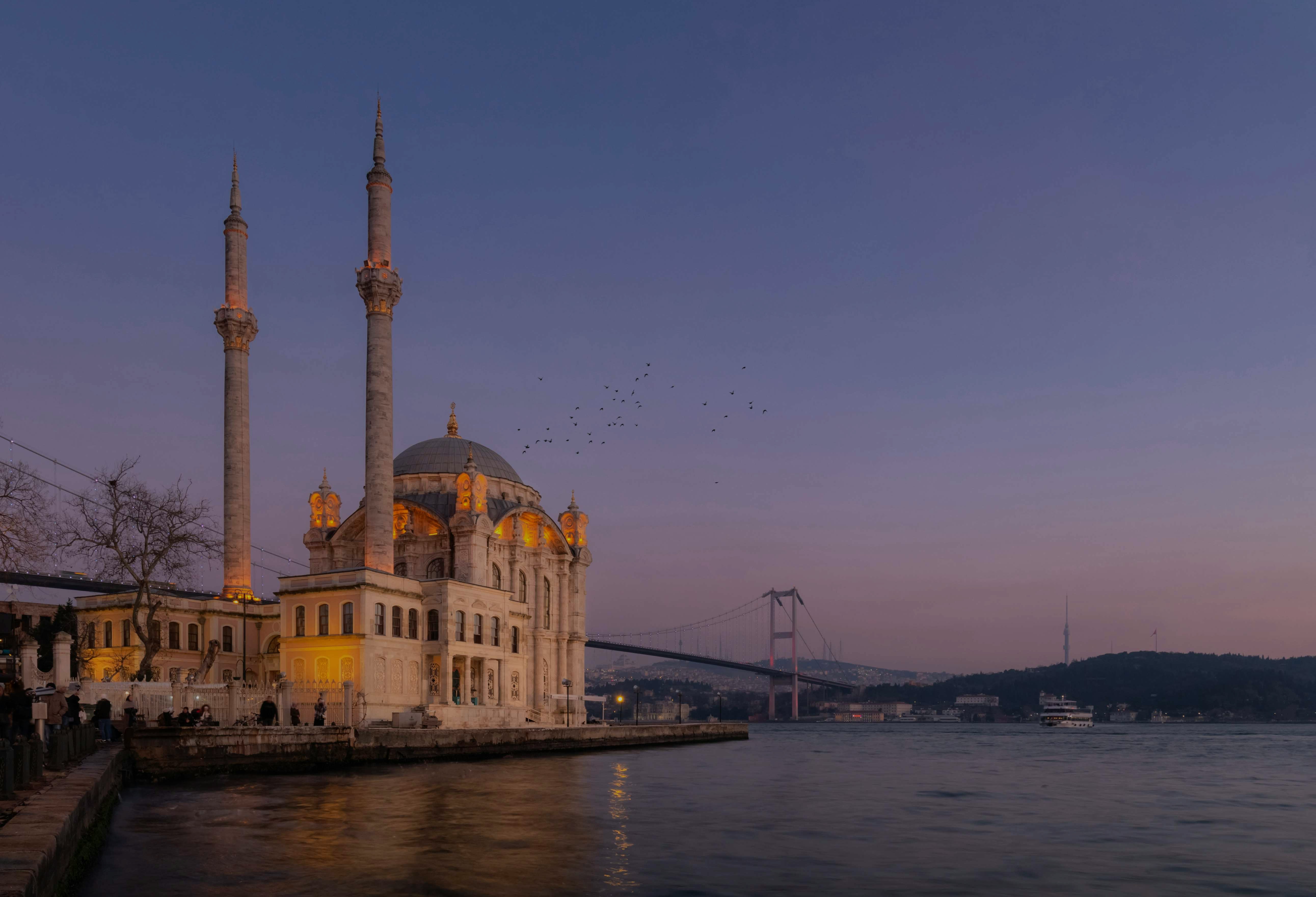 Ortaköy Mosque at sunset near Kabatas Pier, Istanbul, with Bosphorus Bridge in the background.