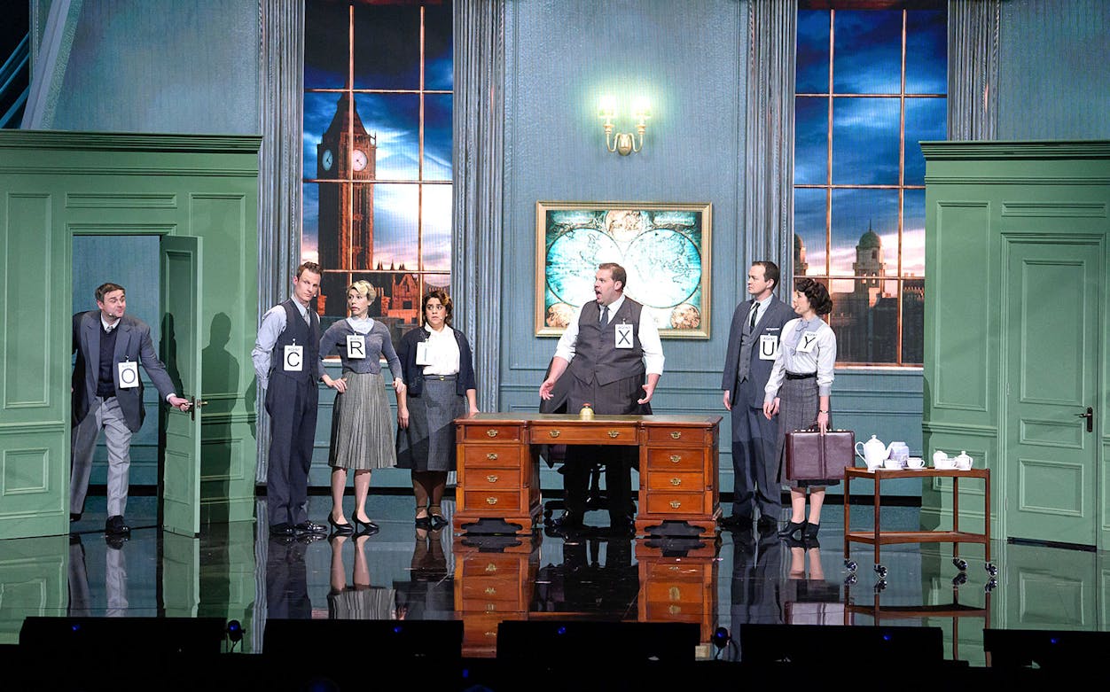 Actors on stage in a comedic spy play set in London with Big Ben visible through the window.
