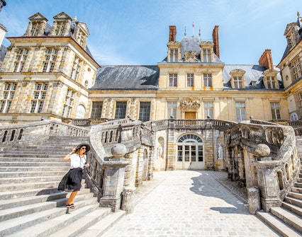 Visitor on grand staircase of Château de Fontainebleau, France.