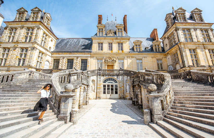 Visitor on grand staircase of Château de Fontainebleau, France.