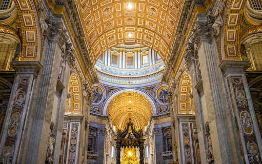 St. Peter’s Basilica interior with ornate ceiling and columns on guided tour.