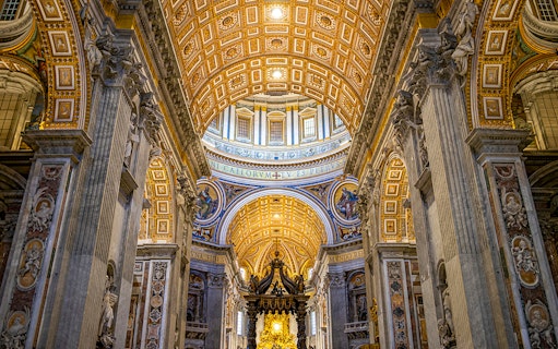 St. Peter’s Basilica interior with ornate ceiling and columns on guided tour.