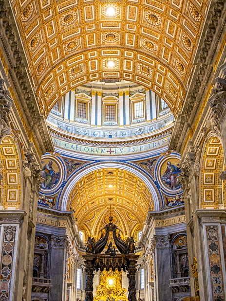 St. Peter’s Basilica interior with ornate ceiling and columns on guided tour.