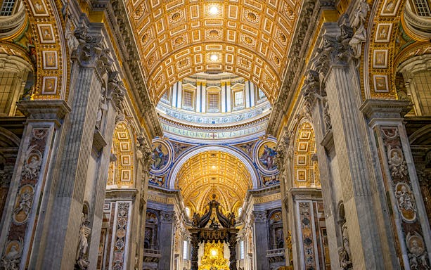 St. Peter’s Basilica interior with ornate ceiling and columns on guided tour.